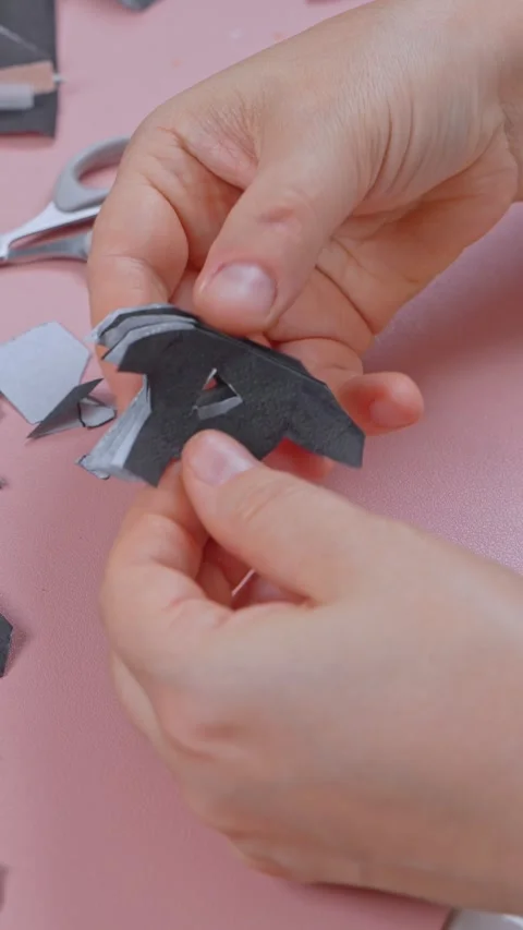 Fingers snipping tiny triangles into a folded dark paper shape with fine sc.. Stock Footage 346960091