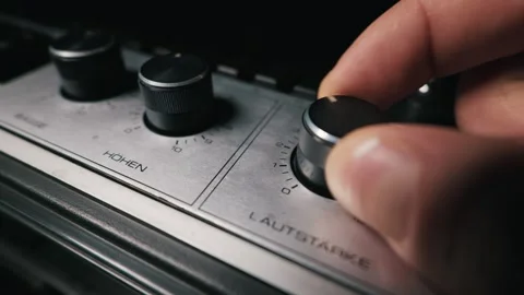 Fingers Turning the Volume Control Knob on a Vintage Audio Amplifier Panel Stockbeeldmateriaal 333818668