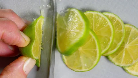 Fingers using a small knife to slice a lime fruit. Stock Footage 221274632