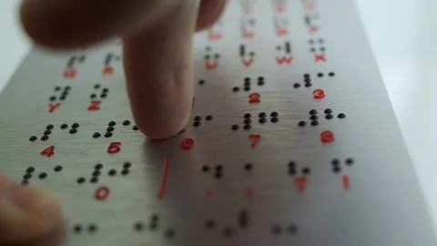 Fingertip gently exploring braille, glasses reflecting the coded language, c Stock Footage 306550790