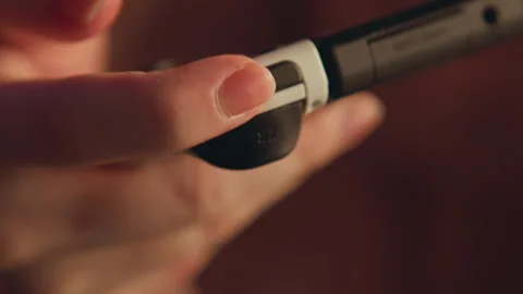 Fingertip pressing rounded side button on handheld electronic device with warm Stock Footage 347618141