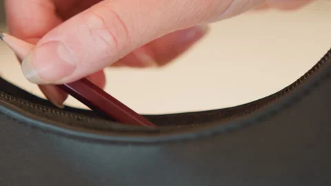 Fingertips pressing thin tool into curved leather upholstery seam, creating Vídeo Stock 343530095
