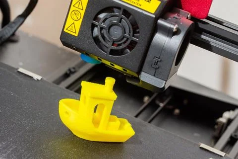 Finished 3D printed model of yellow ABS ship. Detail of printhead with fan and Stock Photos