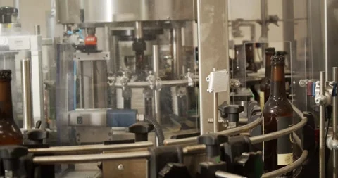 Finished beer bottles exiting automated bottling machine in Berlin brewery Stock Footage 335142667