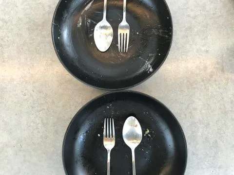 Finished eating of two sets of silver stainless spoon, fork and plate Stock Photos