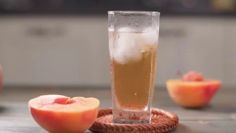 Finished Peach Extract Juice With Ice Cubes In Glass Slow Slider Shot Stock Footage 344050717