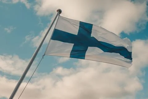 Finnish flag with clouds in the background on a summer day Stock Photos