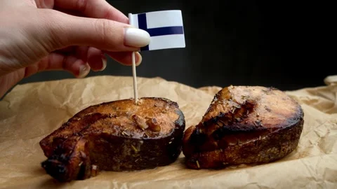 Finnish flag stuck into salmon, symbol of Baltic Sea fish from Finnish waters. Stock Footage 323010044