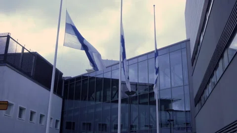 Finnish flags at half-mast with a contemporary building on a background Stock Footage 236016002