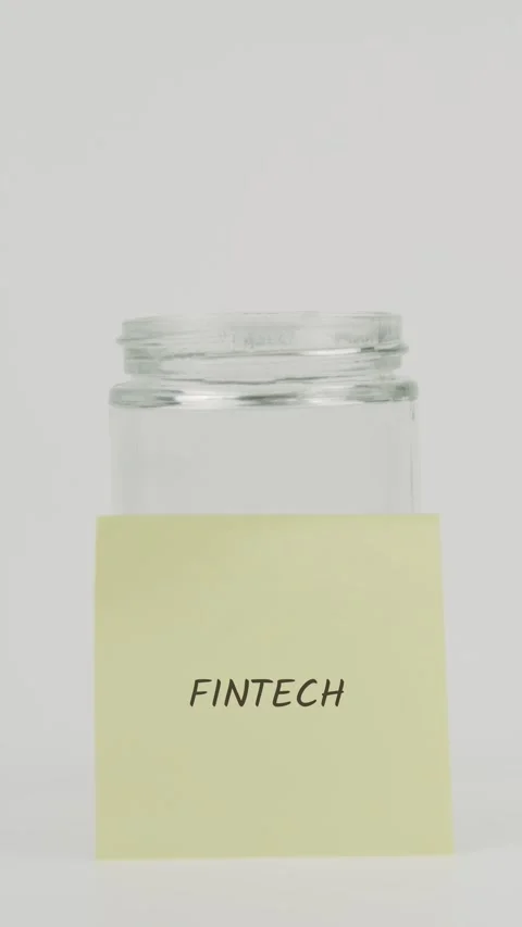 Fintech text or word on yellow sticky note attached to glass jar with hand Stock Footage 311733734