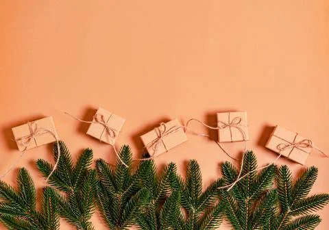 Fir branches and craft gift boxes on a beige background. Stock Photos