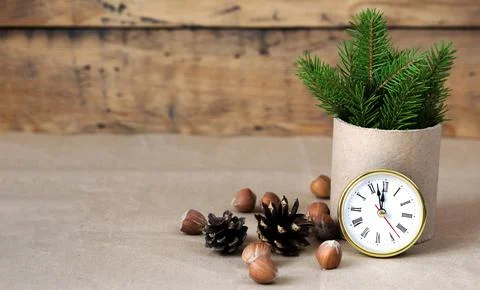 Fir branches, clocks, nuts and cones on a wooden background. Eco decoration f Stock Photos