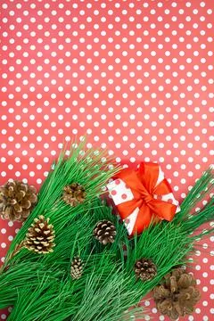 Fir branches with cones, gift box with bow on red background with polka dots Stock-Fotos