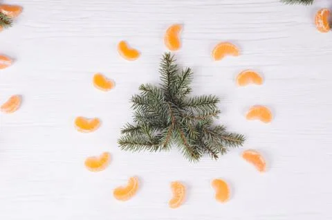 Fir branches at form of tree  and tangerines around it on wooden white backgr Stock Photos