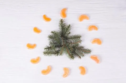 Fir branches at form of tree  and tangerines around it on wooden white backgr Stock Photos