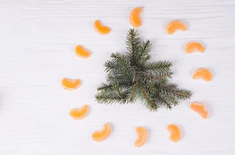 Fir branches at form of tree  and tangerines around it on wooden white backgr Stock Photos
