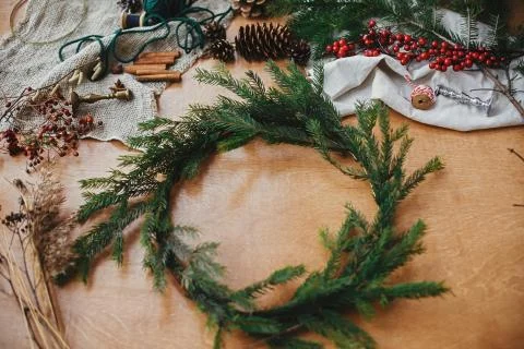 Fir branches, pine cones, thread, berries, cinnamon on wooden table. Rustic C Stock Photos