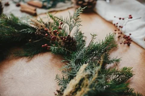 Fir branches, pine cones, thread, berries, cinnamon on wooden table. Rustic C Stock Photos