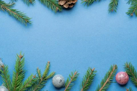 Fir, spruce branches, pine cones and Christmas tree toys on blue background w Stock Photos