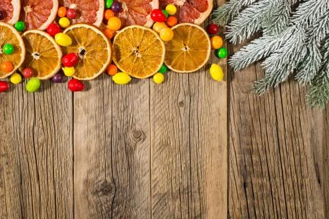 Fir tree branch with orange, grapefruit and candy on an old wooden table. Stock Photos