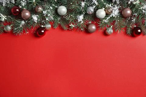 Fir tree branches with Christmas decoration on red background, flat lay. Spac Stock Photos
