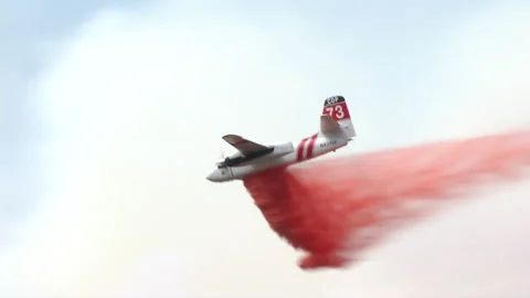 Fire aircraft plane drops red fire retardant during wild fire Stock Footage 219303542