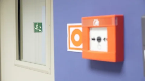 Fire alarm button and exit direction sign on stairs in office Stock Footage
