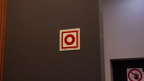 Fire alarm call point sign on dark wall with prohibition sign below Stock Footage 337514685