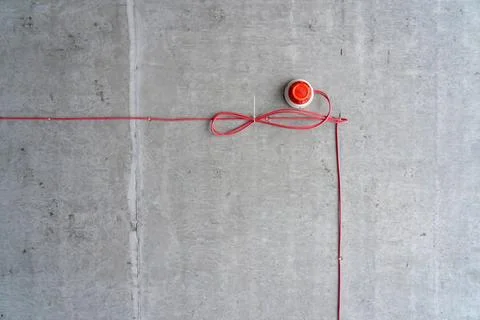 Fire alarm device with red electrical wiring mounted on raw concrete wall Stock Photos