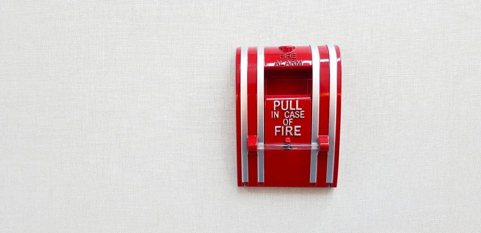 Fire alarm switch box for pull in case of fire isolated on grey or gray wall Stock Photos