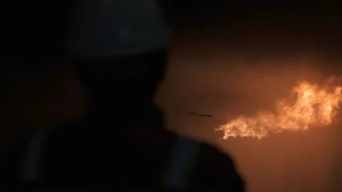 Fire and Engineer in helmet. Associated gas is burning. Well testing. Drilling Stock Footage 229895589