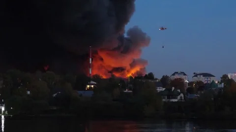 Fire and explosions in the city. A rescue helicopter extinguishes fire risking Stock-Footage 80959817