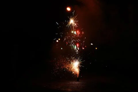 Fire and multi-colored sparks from the explosion of a fire pit on a dark Foto stock