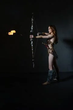 Fire archer prepares to shoot an arrow in a darkened studio setting Stock Photos