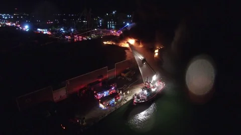 Fire boat putting water on large warehouse fire at port Stock Footage