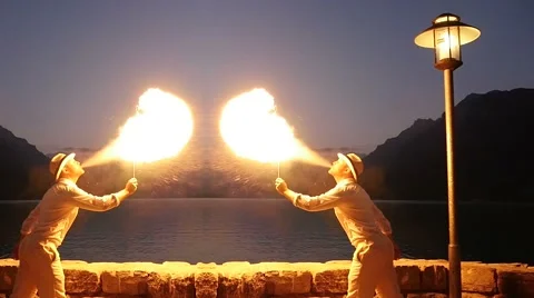 Fire breather spitting fire outdoors in front of lake at night Video stock 42942157