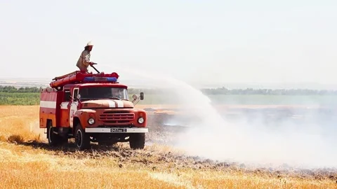 The fire brigade drives a fire engine and puts out a fire in an agricultural Stock Footage 155580287