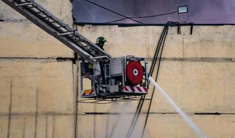 The fire brigade, standing on the fire escape, extinguishes a fire in an indu Stock Photos