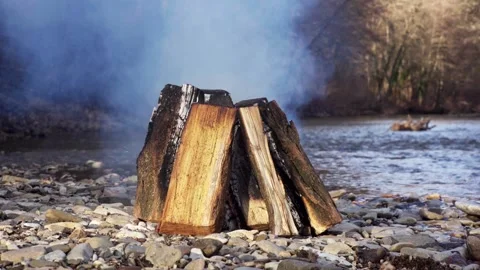 A fire is burning on the bank of a mountain river Video stock 263136980