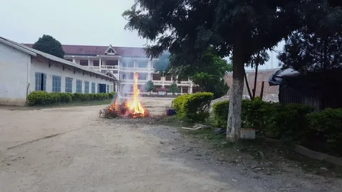 Fire burning branches and things in school yard next to tree, Sam Neua, Laos Vídeos de archivo 76793328