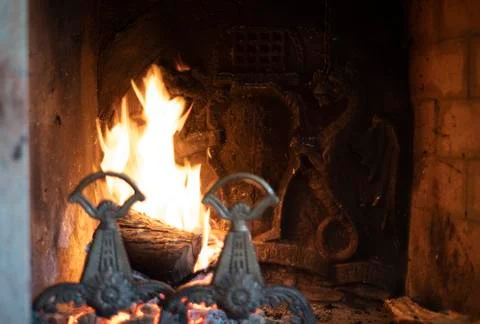 Fire burning in a dragon fireplace in an old house Stock Photos