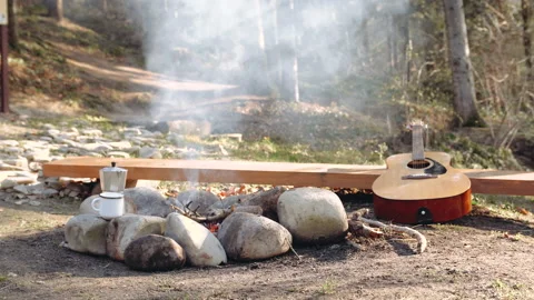 Fire is burning in the forest, there is smoke, and a guitar is lying next to it Stock Footage 195204974