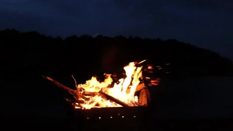 A fire is burning in the grill. Bonfire is burning near the river and forest on Video stock 159353877