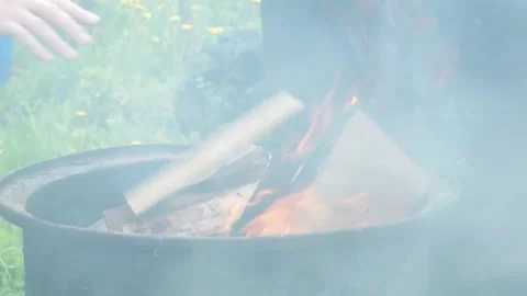 Fire burning inside old barrel, hand throws logs Stock Footage 196473171