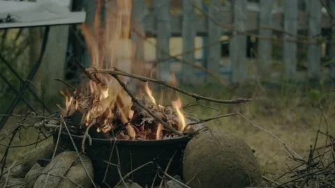 A fire is burning, a man throws branches Video stock 196993932