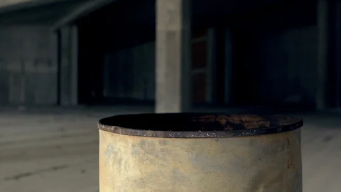 A fire burning in a metal barrel in the middle of an abandoned building. Stock Footage 90209232