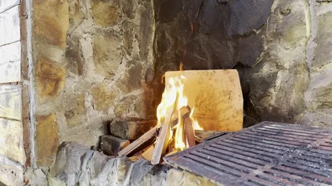 Fire burning in rustic stone fireplace outdoors Video stock 333707455