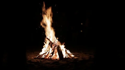 Fire burning on sandy beach late at night, people’s silhouettes seen around 動画素材 115930927