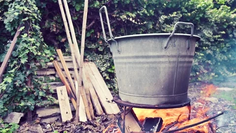 Fire burning under an old pot, scene taken outside, vintage old fashioned Stock Footage 232798182