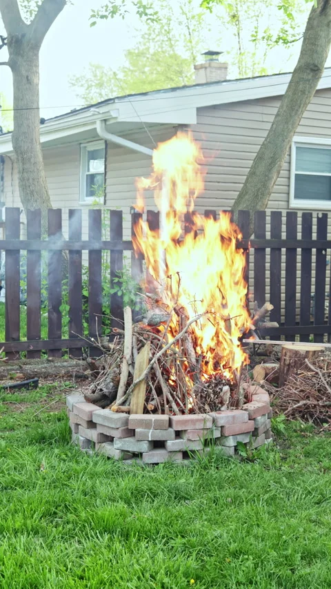 Fire burns in backyard as branches and sticks create flames in early evening Stock Footage 337902743